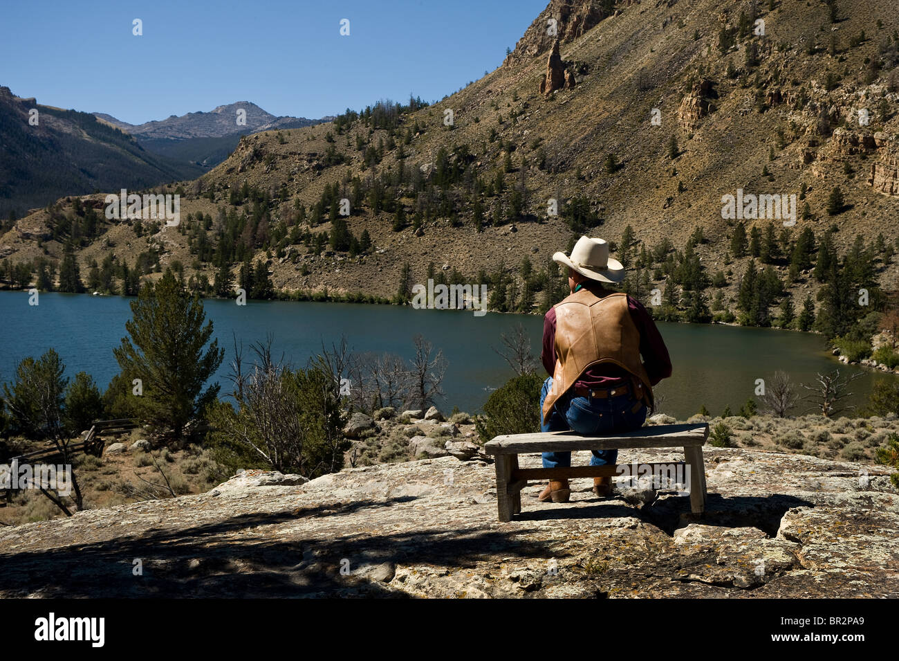 Cowboy sitting looking ahead at the beautiful lake. Lonesome cowboy
