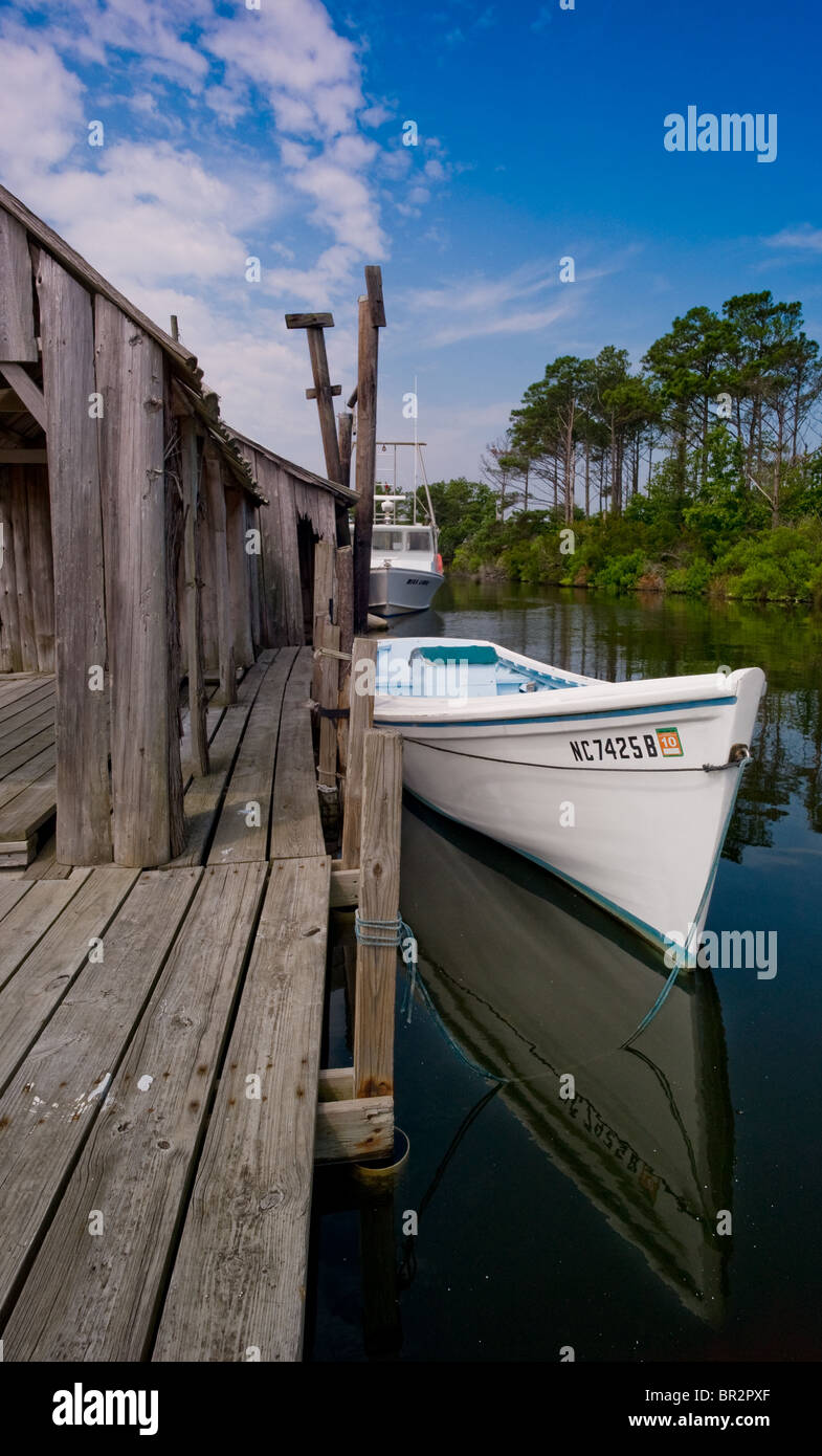 A fishing skiff is tied to a fish house in Manns Harbor, North Carolina. Stock Photo