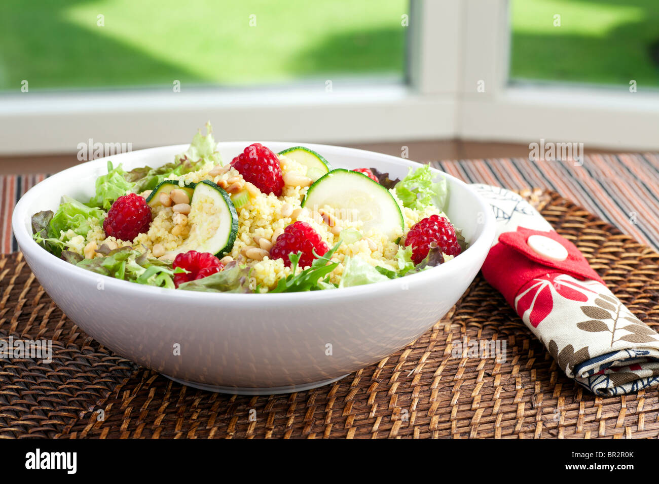 Couscous salad with zucchini and raspberries and pine nuts. Stock Photo