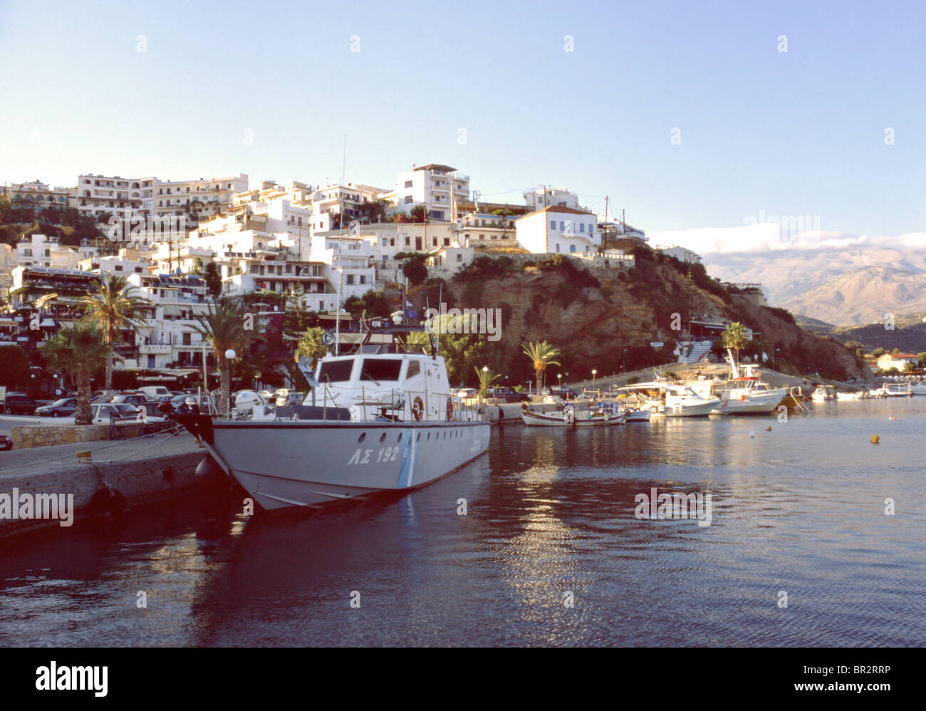 A Greek coastguard vessel moored at Agia Galini harbour in Crete, with cloud-capped mount psiloritis in the background. Stock Photo