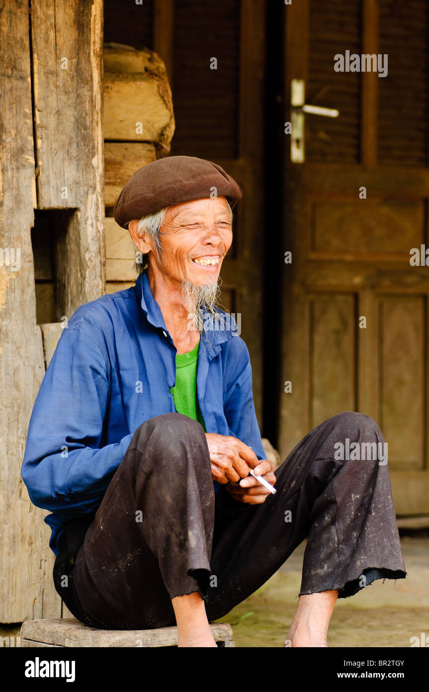 Old smiling Vietnamese man having a smoke outside his house in Sapa ...