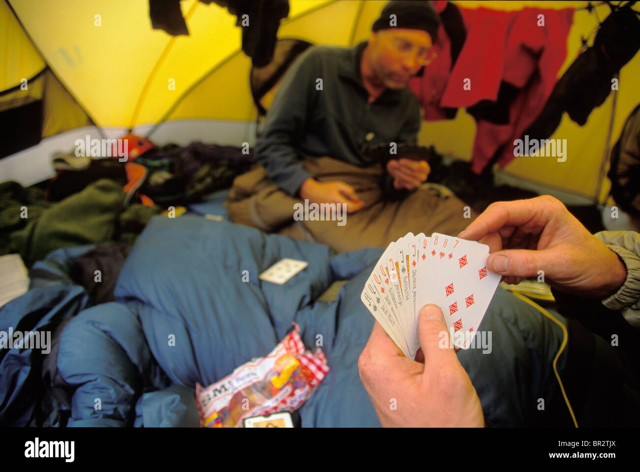 Two men/climbers playing cards in a tent. Stock Photo