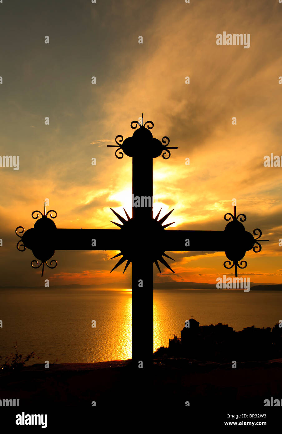 Iron cross with monastery in the bottom right in the sunset on Mount Athos, Greece Stock Photo
