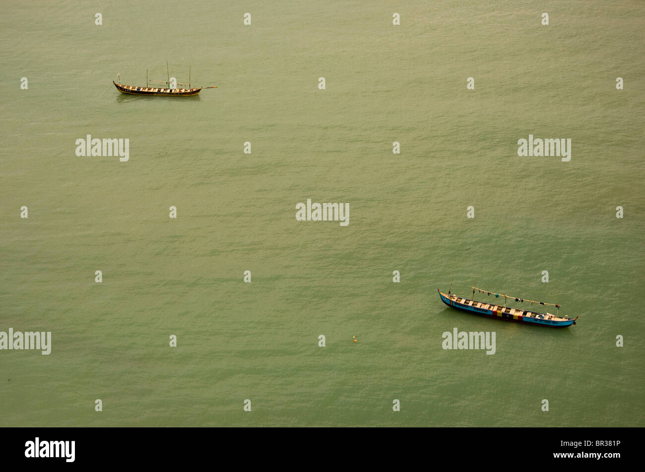 Two small traditional Ghanaian fishing boats at anchor in calm midday waters off the shore of  Cape Coast. Stock Photo