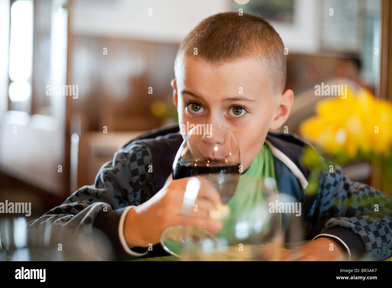 Cute kid drinking soda from a glass, in a restaurant Stock Photo