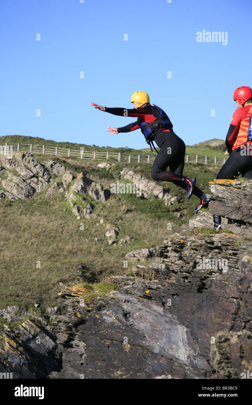Coasteering Cornwall; Man jumping off a cliff into the sea Stock Photo