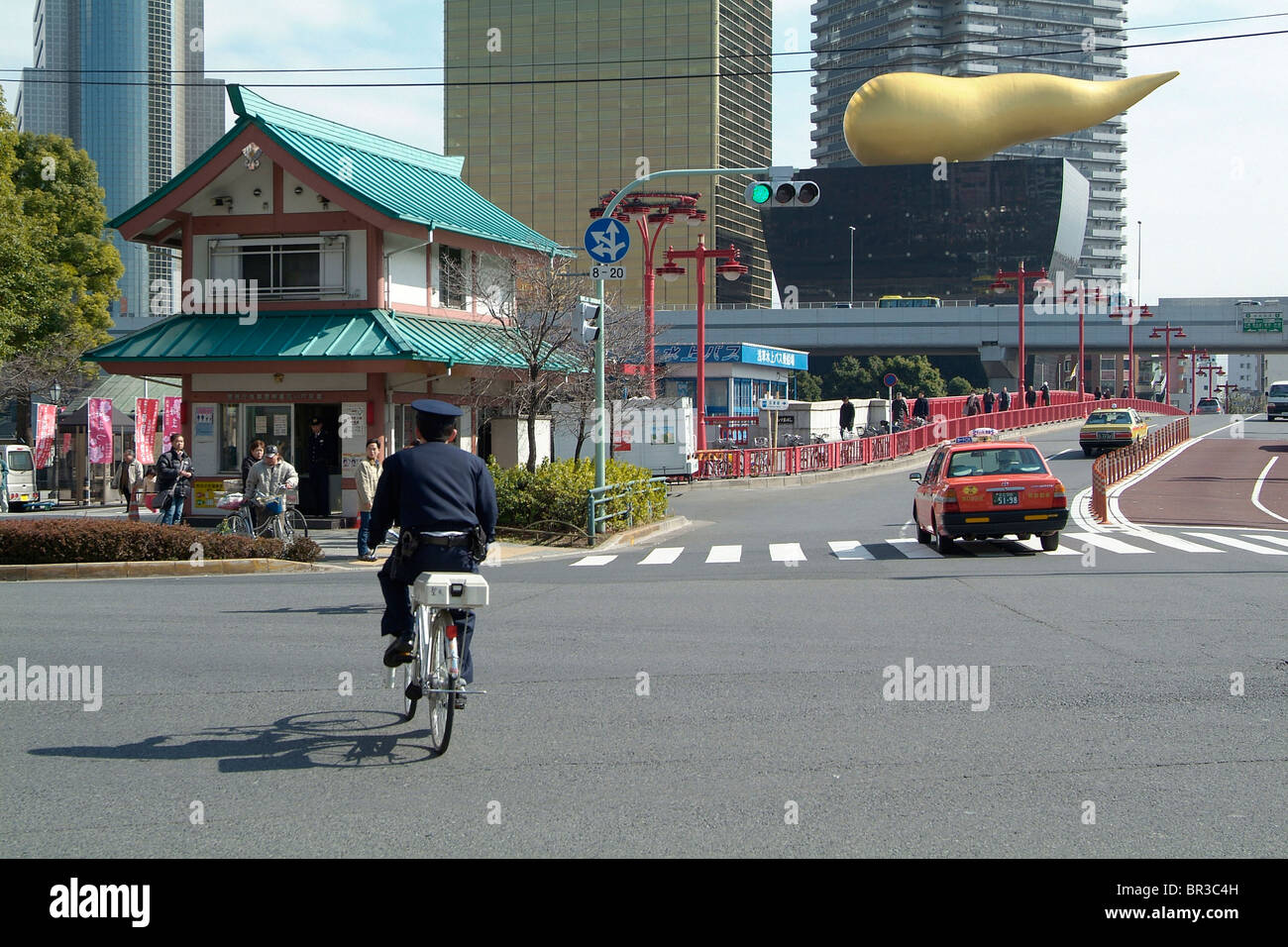 Japanese policeman on bicycle, Asahi Beer Headquarters Building in background Stock Photo