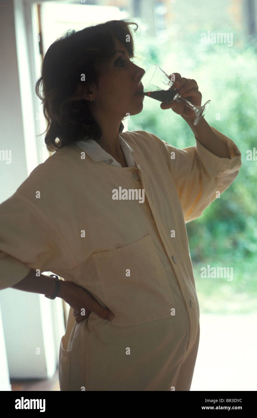 pregnant woman drinking a glass of red wine in profile Stock Photo