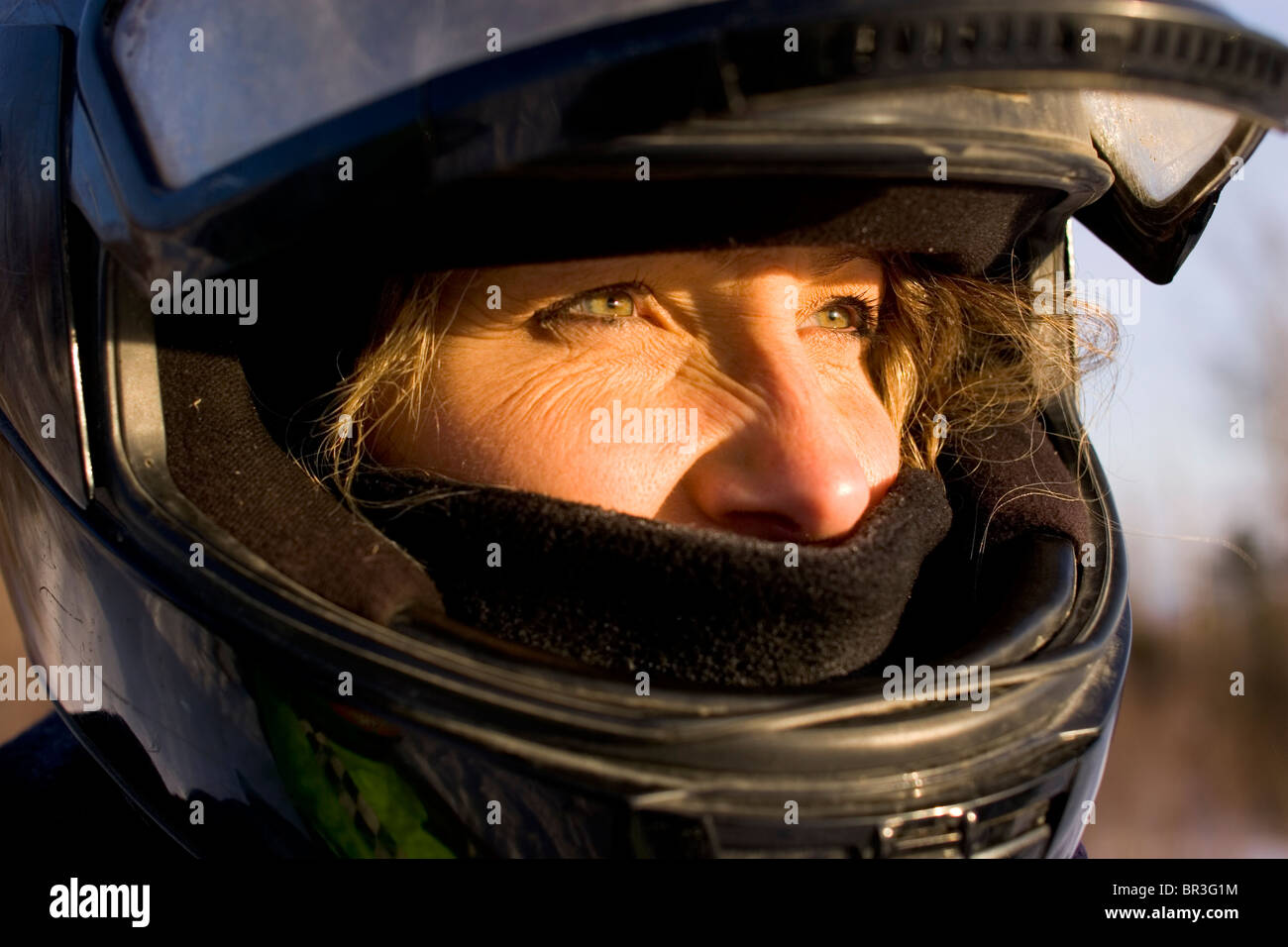 Portrait of a woman wearing her snowmobiling helmet in Maine. (close-up) Stock Photo