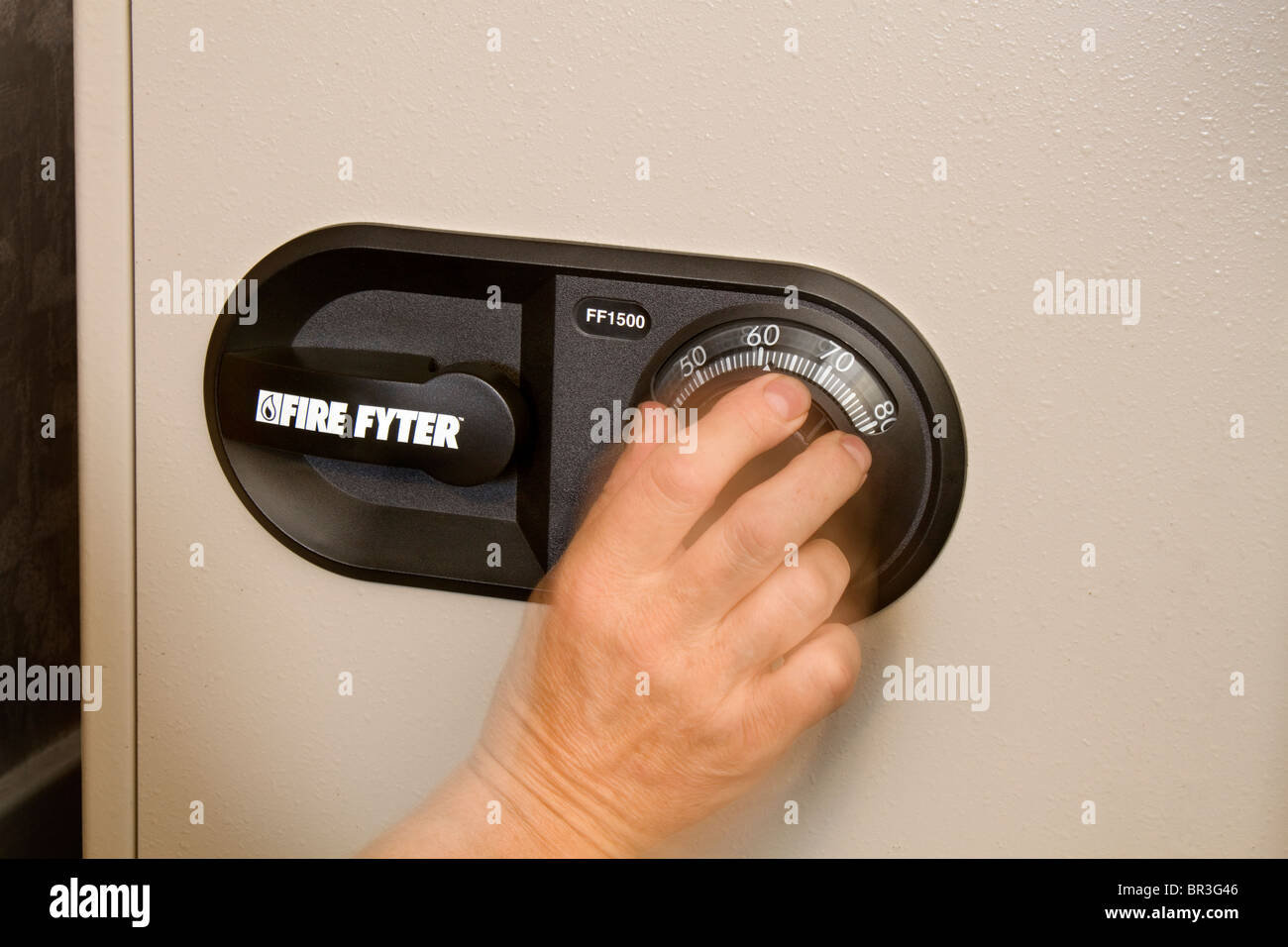 A mans hand is shown rotating the dial while opening a fireproof safe Stock Photo