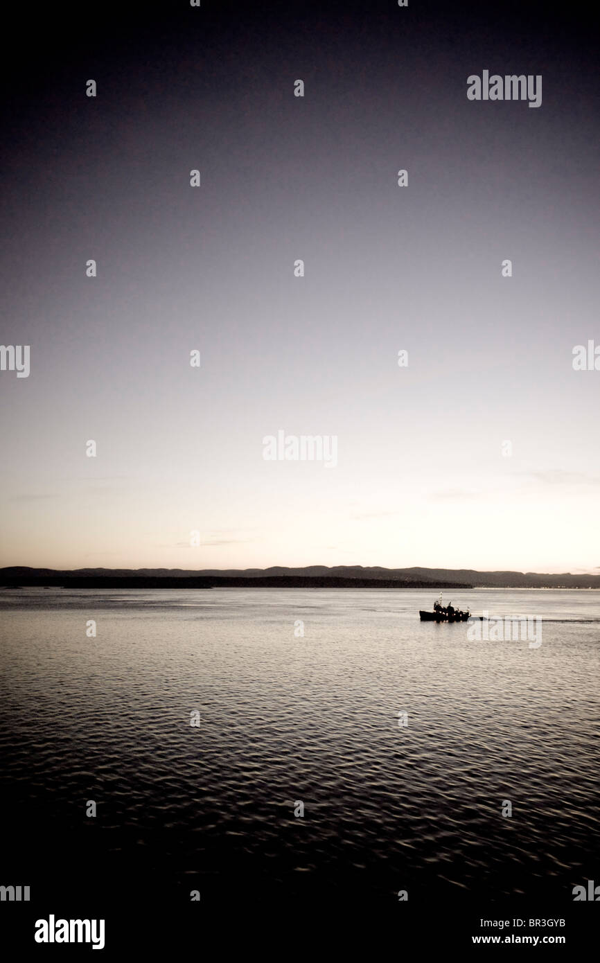Fishing boat on the Pacific ocean at sunset (toned image). Stock Photo