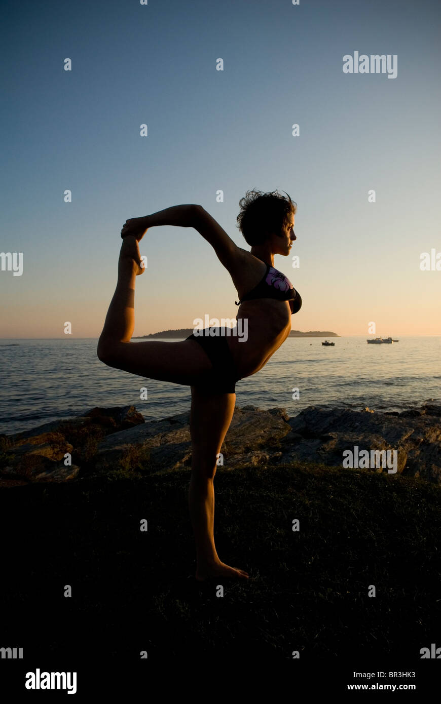 Woman practicing yoga on the coast of Maine at sunset, New England. Stock Photo
