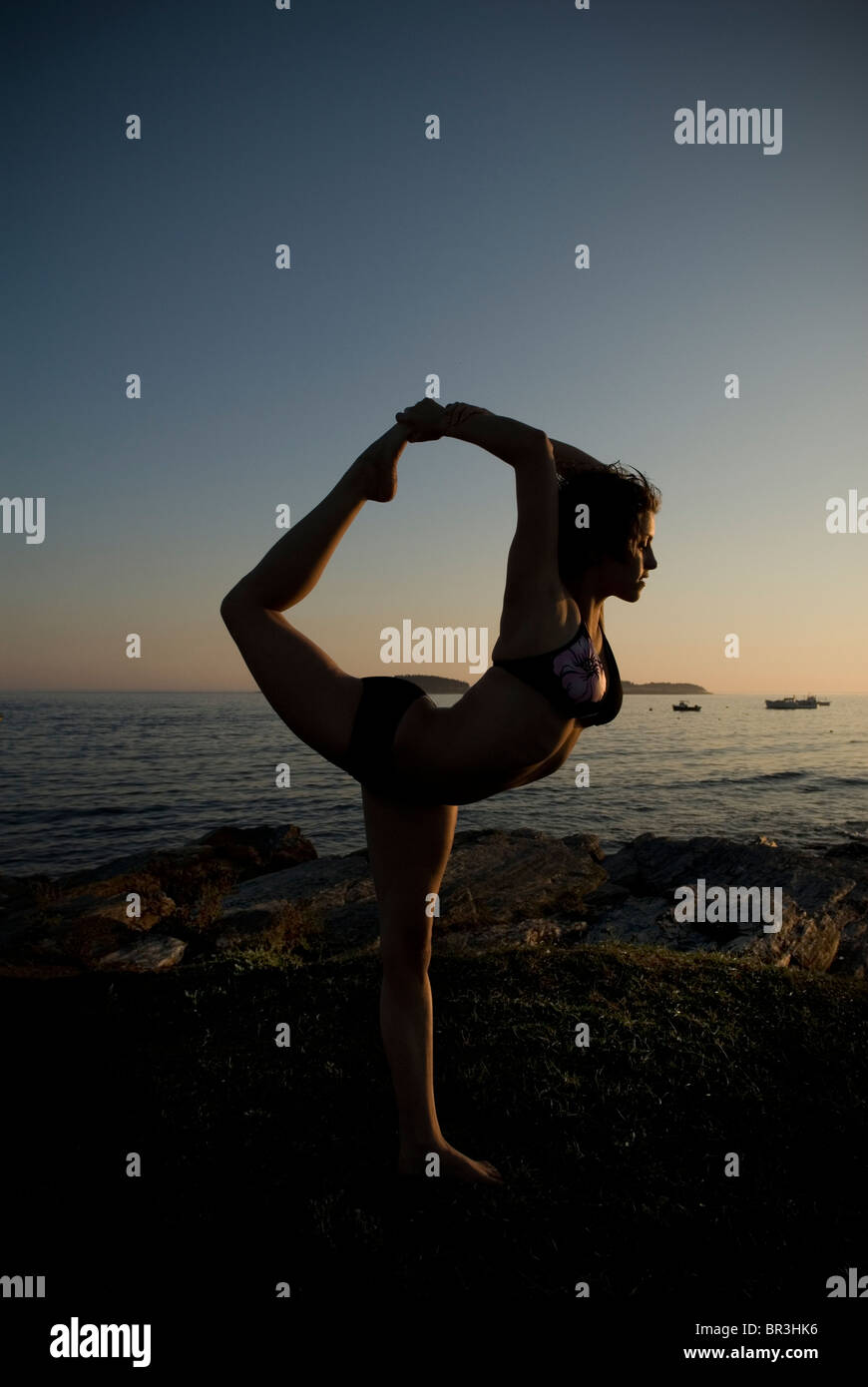 Woman practicing yoga on the coast of Maine at sunset, New England. Stock Photo