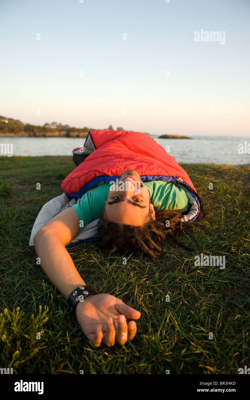 Man inside sleeping bag on the coast of Maine, New England. Stock Photo
