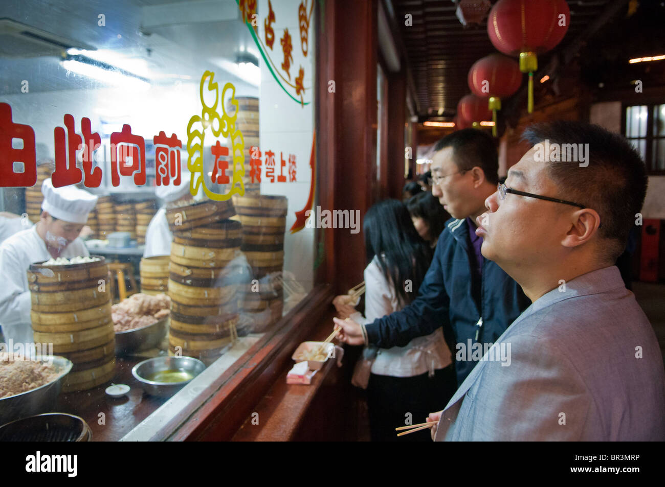 Man savors snack outside won ton restaurant, Yuyuan Gardens and Bazaar, Shanghai, China Stock Photo