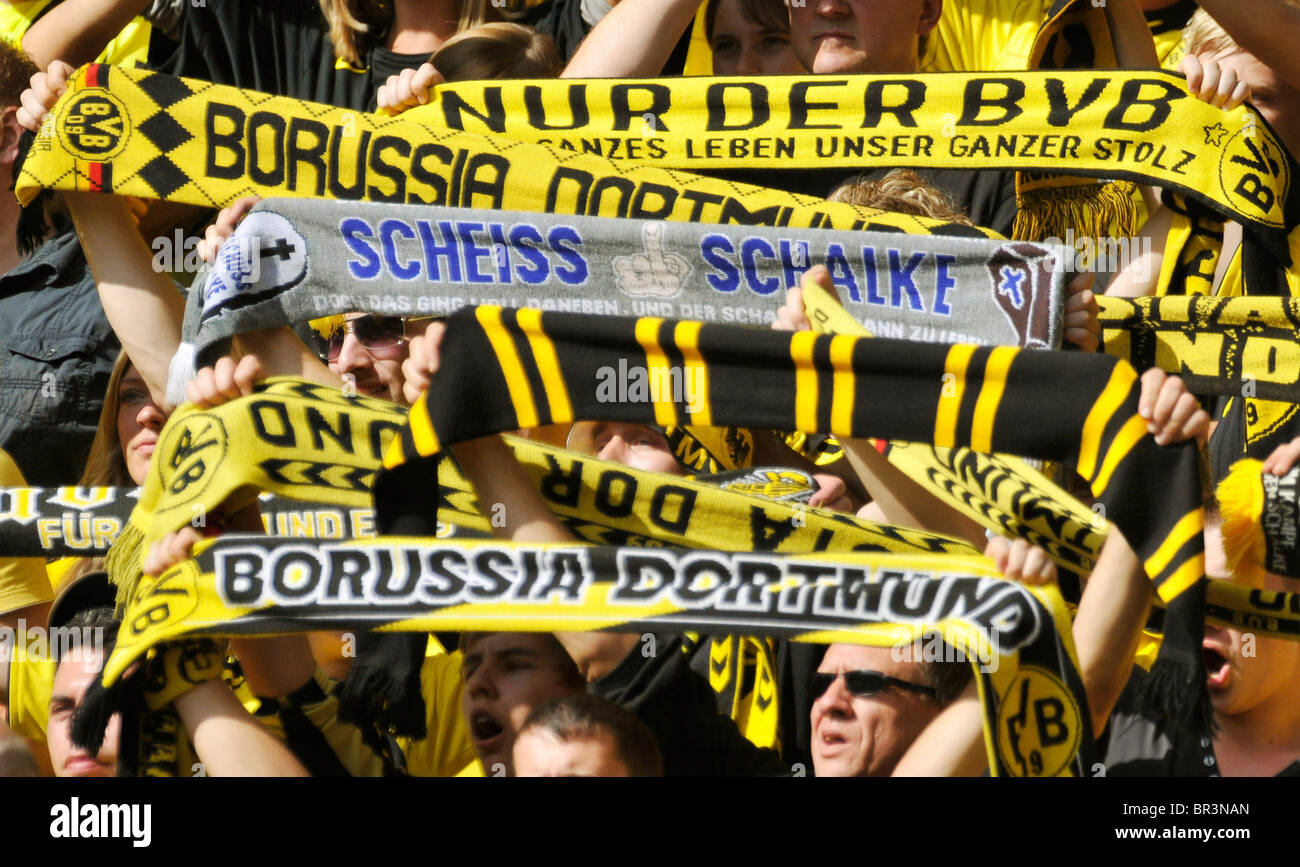 Fans of german football club Borussia Dortmund display scarves with their team colors. The blue scarf insults rival club Schalke Stock Photo