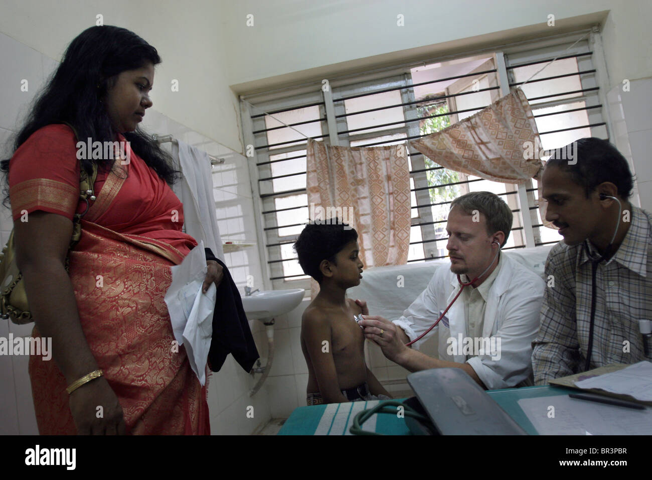A western Swedish doctor investigates a young child patient at a hospital in Trivandrum (Thiruvananthapuram) in Kerala in India. Stock Photo