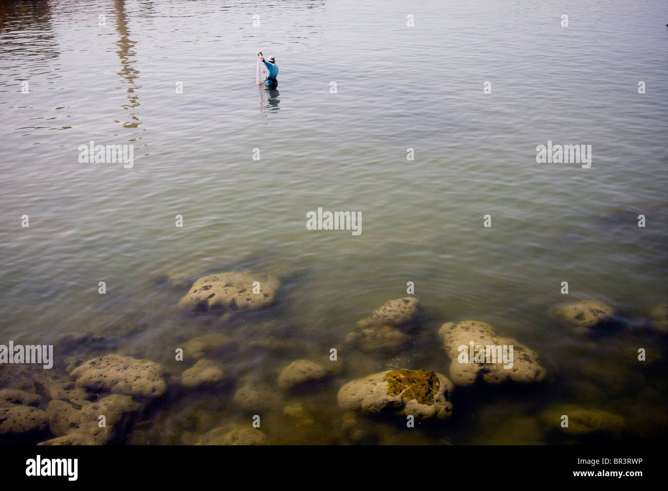 A man is dishing with a net in the old harbor of the historical town of Sidon (Saida) in southern Lebanon. Stock Photo