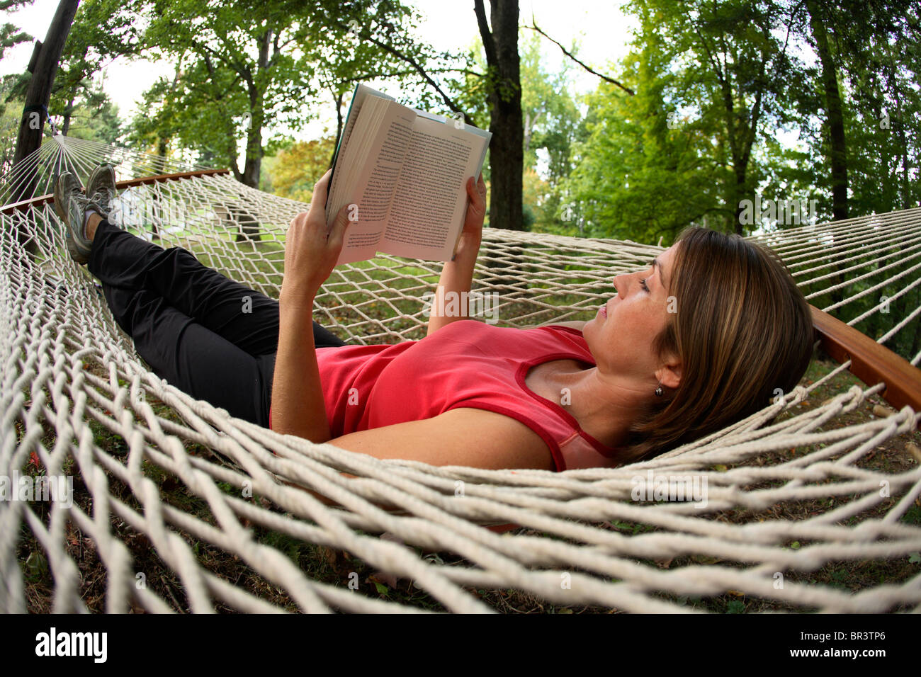 Young woman reading a good book in a hammock in her backyard in Fayetteville, WV Stock Photo