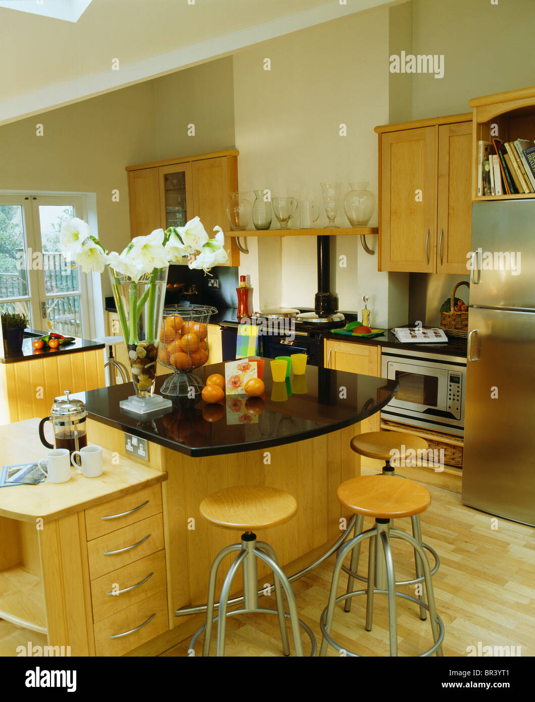 Chrome+wood stools at breakfast bar with black granite worktop in