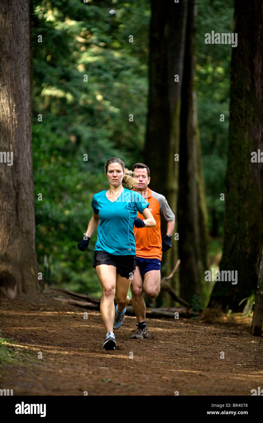 Man and woman trail running in the woods. Stock Photo