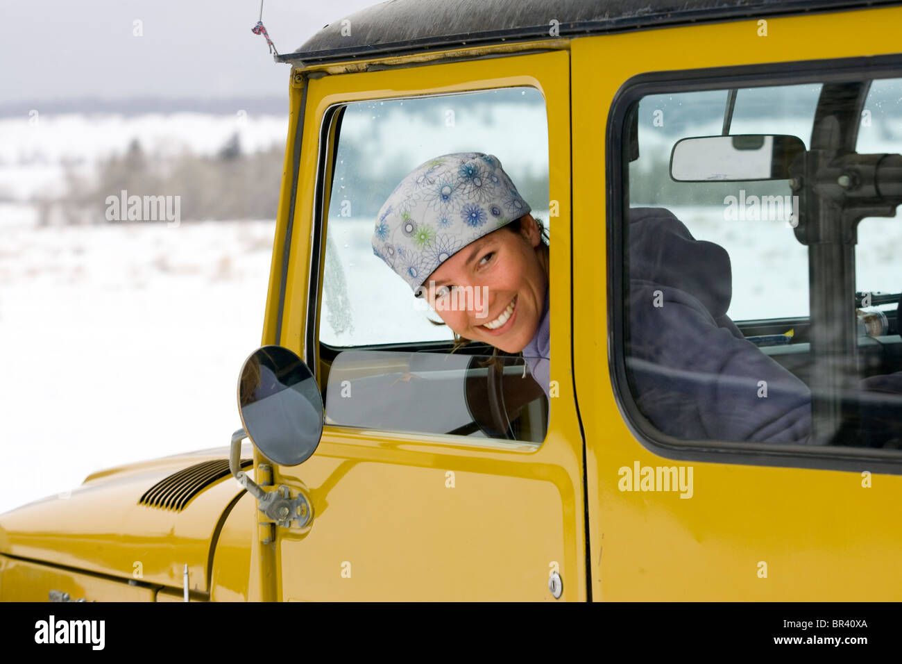 A young woman smiles while reversing her truck in Jackson, Wyoming Stock Photo