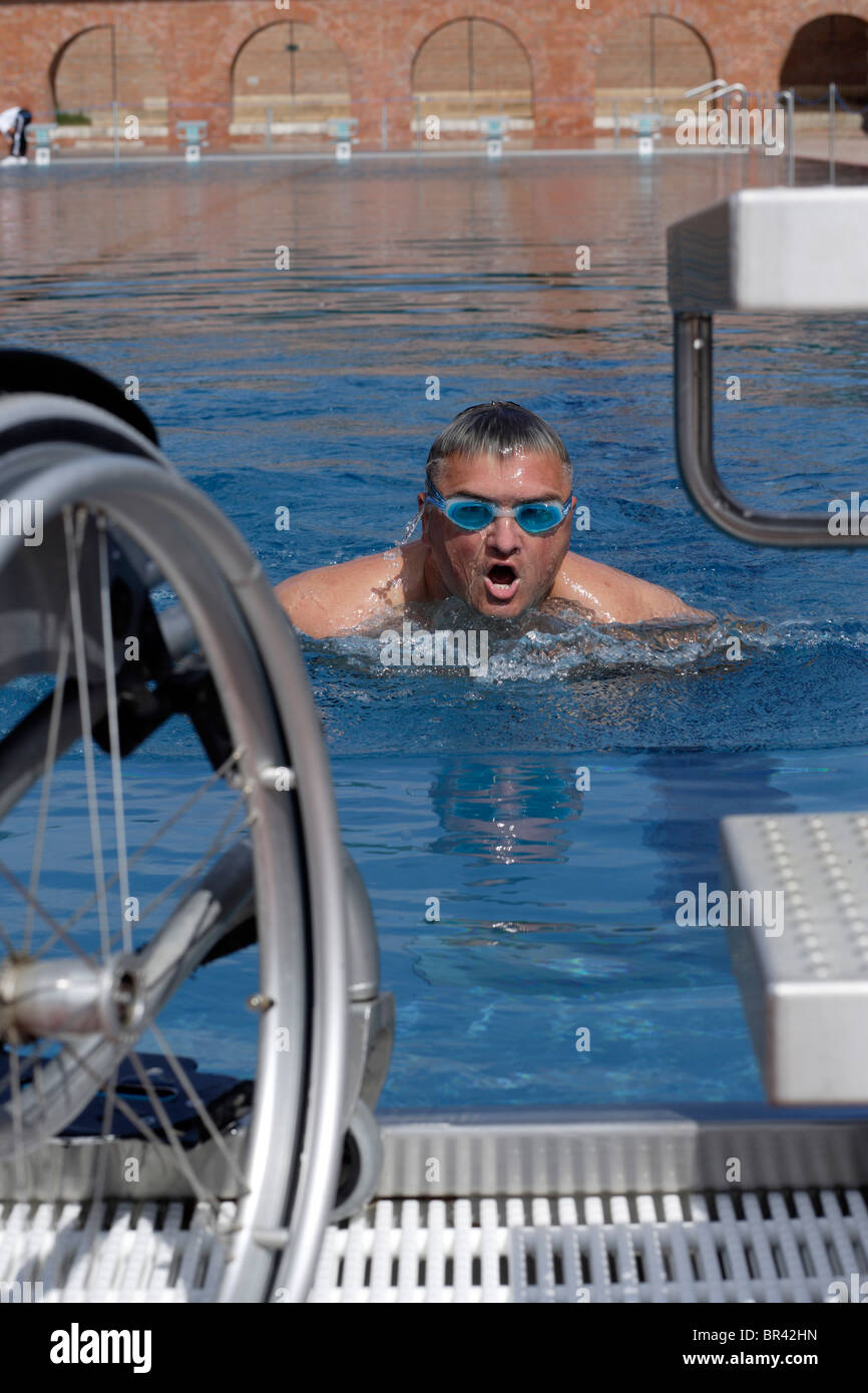 Young, handicapped man, wheelchair user, swimming exercises in a ...