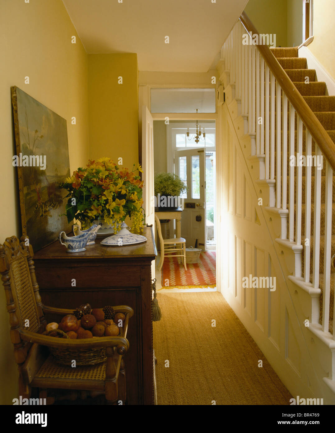 Vase of flowers on antique cupboard in traditional cream hall with