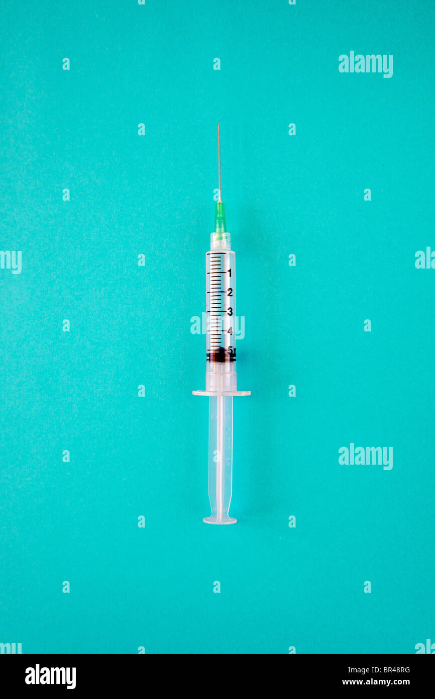 Syringe with needle on blue surface Stock Photo