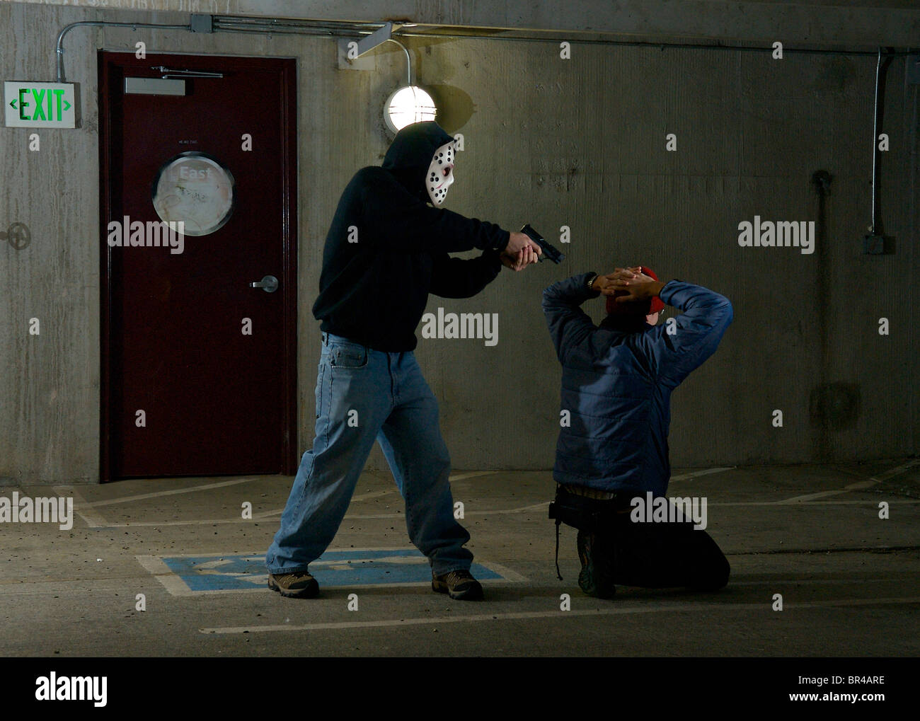 A man being robbed in a parking garage. Stock Photo