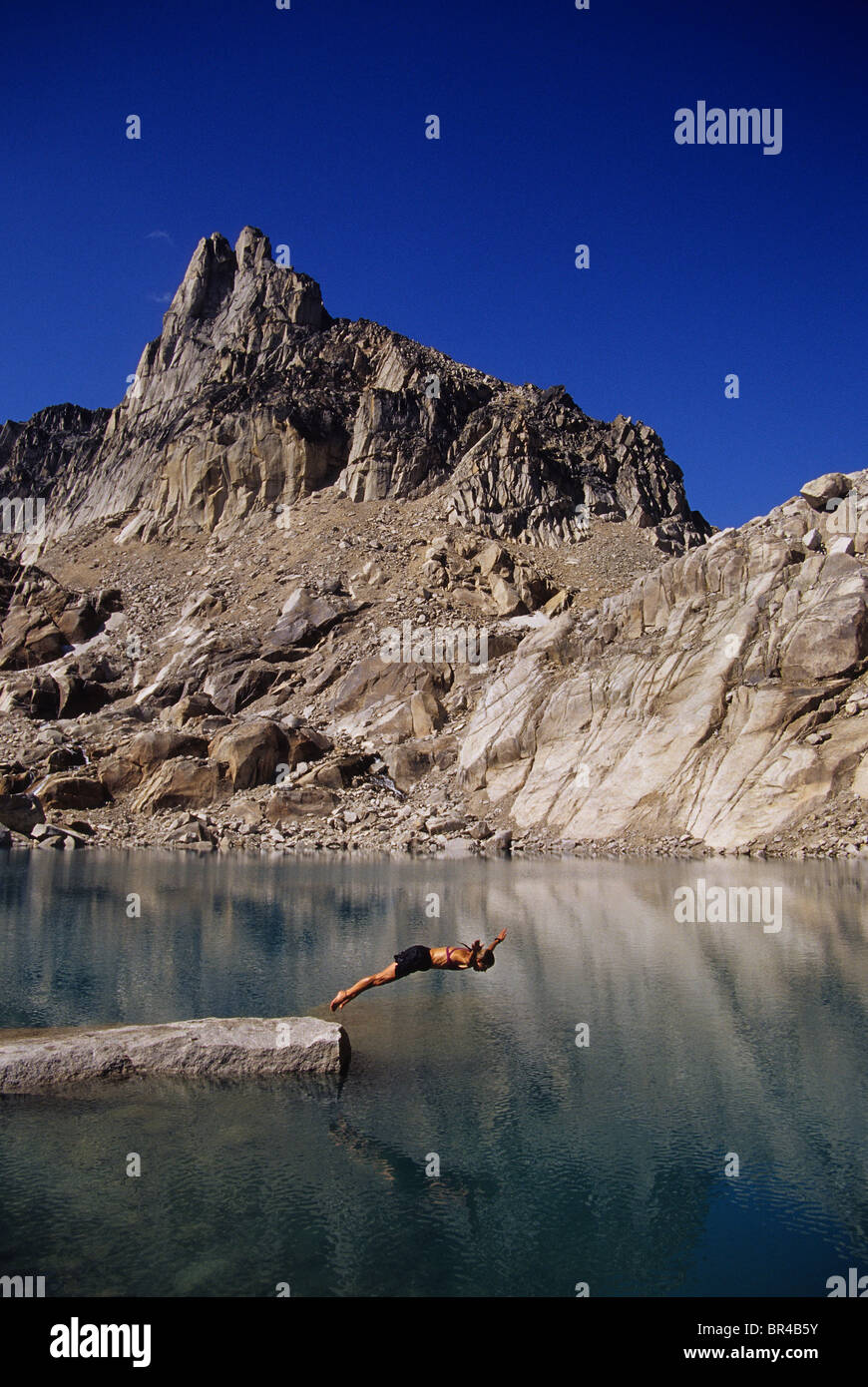 A woman diving into a mountain lake, Bugaboos, Canada Stock Photo