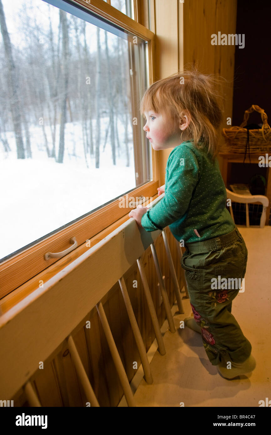 A baby girl looking out a window, Newry, Maine. Stock Photo