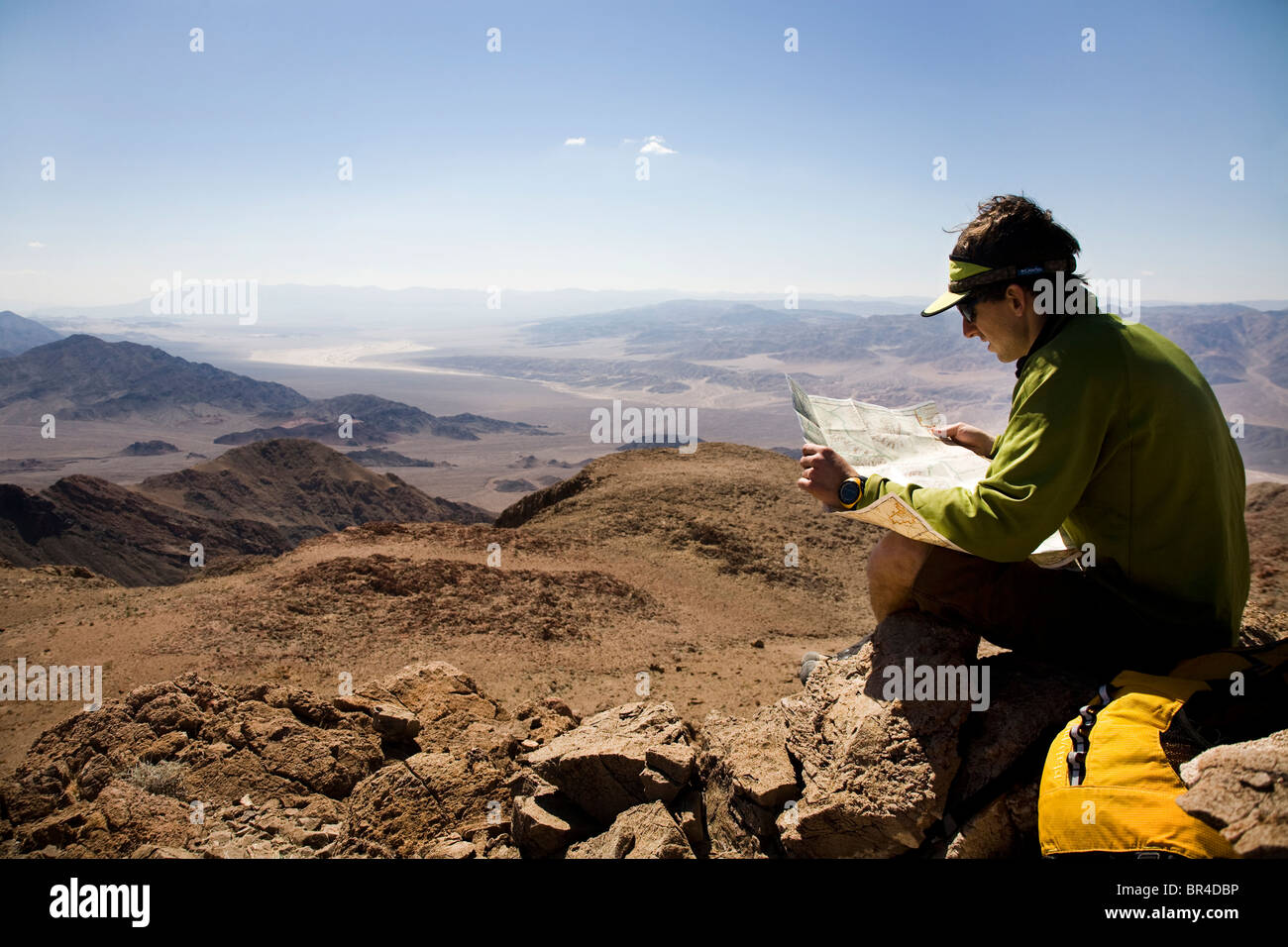 A man looks at a map while sitting on the summit of a peak in Death ...