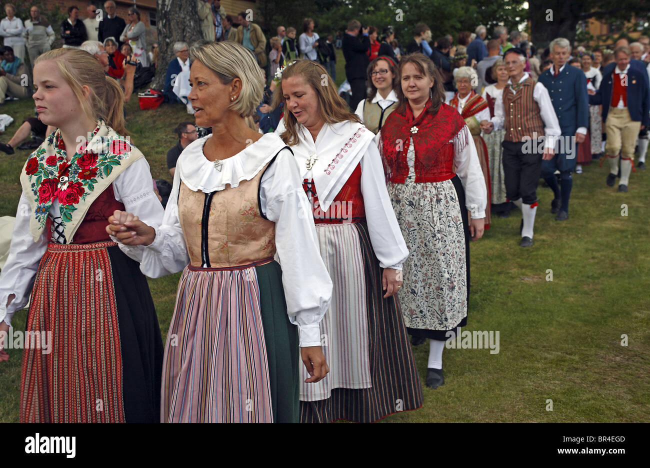 Couples in traditional Swedish folk costumes parade at midsummer celebration. Naas castle estate; Sweden Stock Photo