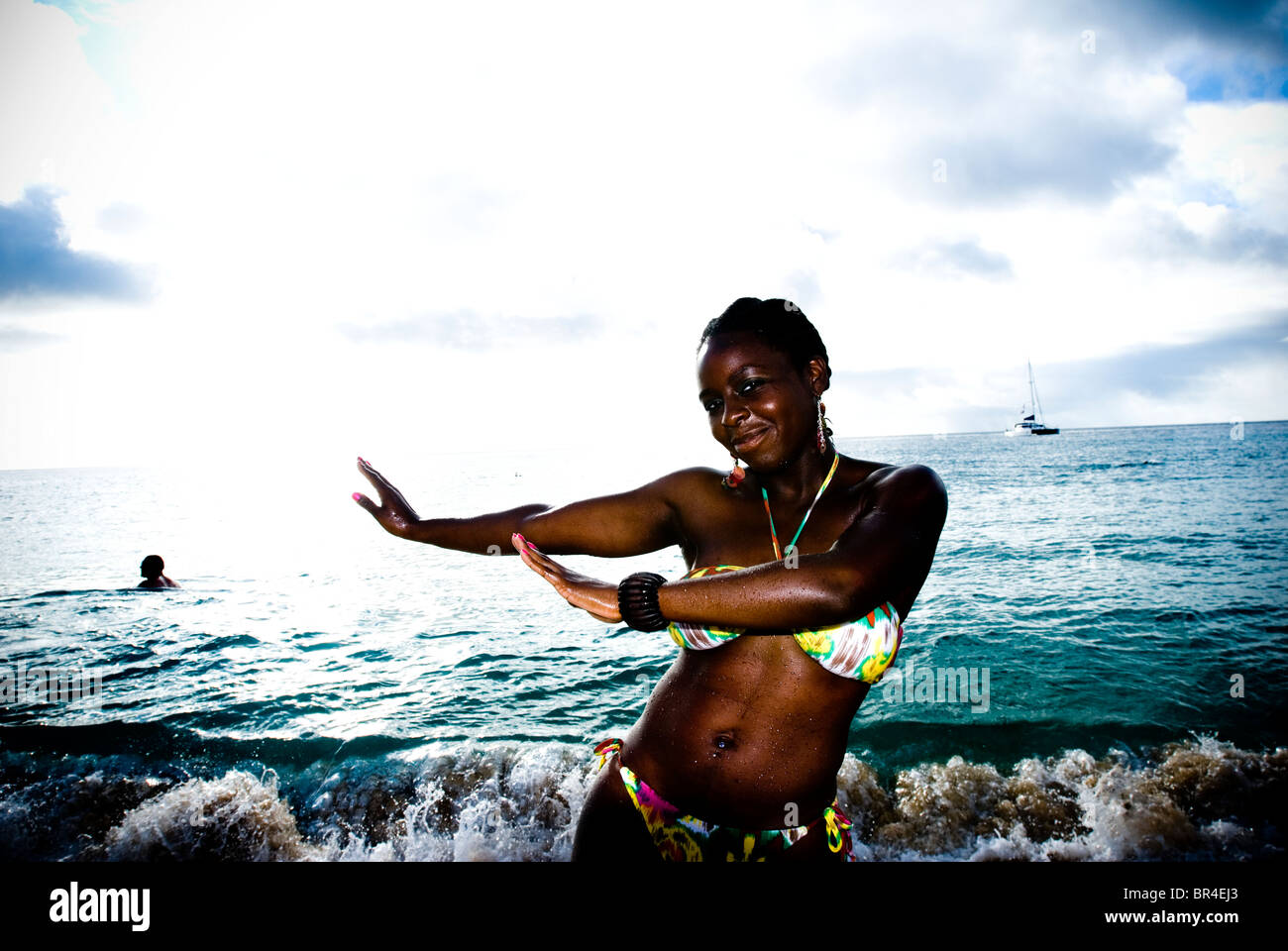 A young African American woman hula dances on the beach at Waimea Bay in Hawaii. Stock Photo