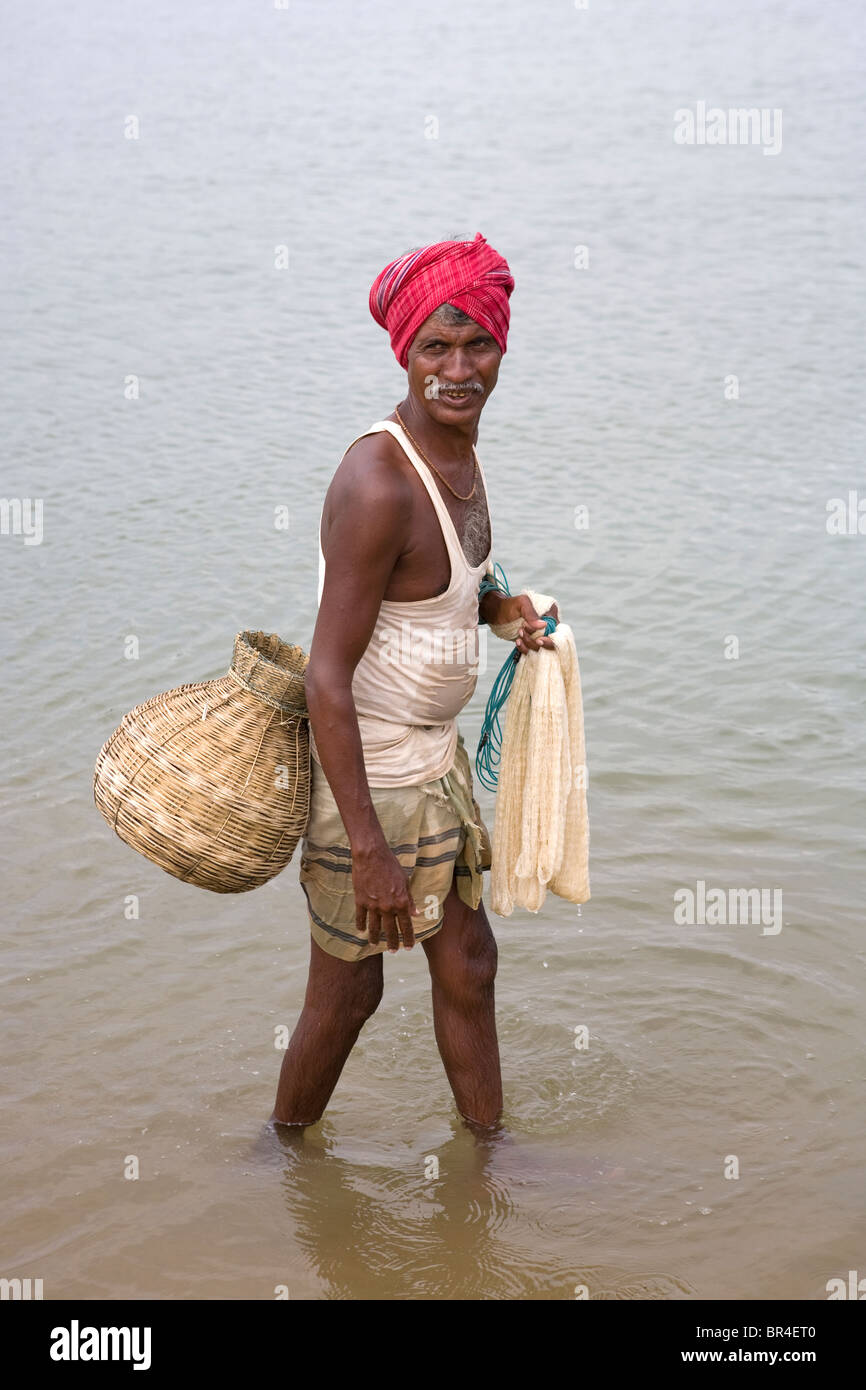An Indian fisherman with a basket is fishing by net near the fishing village in Gopalpur on-Sea, Orissa, India. Stock Photo