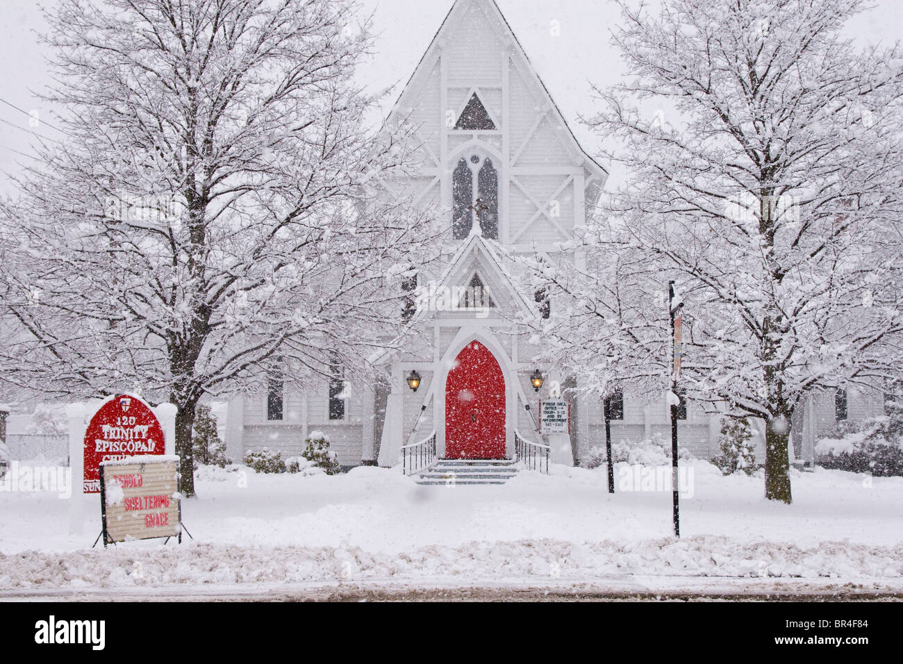 White church with red door in winter snowstorm Stock Photo