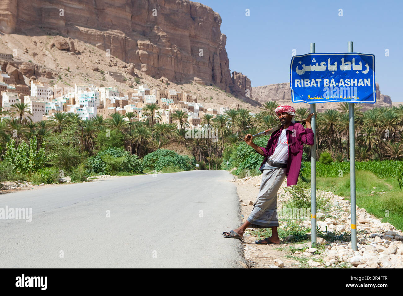 Man standing with AK-47 outside Ribat Ba-Ashan Wadi Do'an, Hadramaut, Yemen Stock Photo