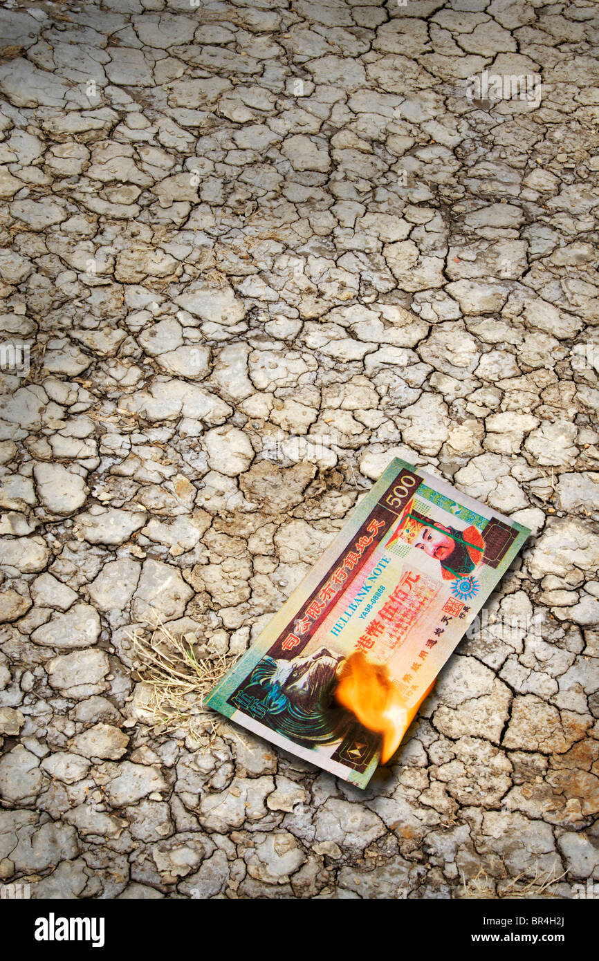 Chinese fake Hellbank, joss paper money burning on scorched earth. Stock Photo