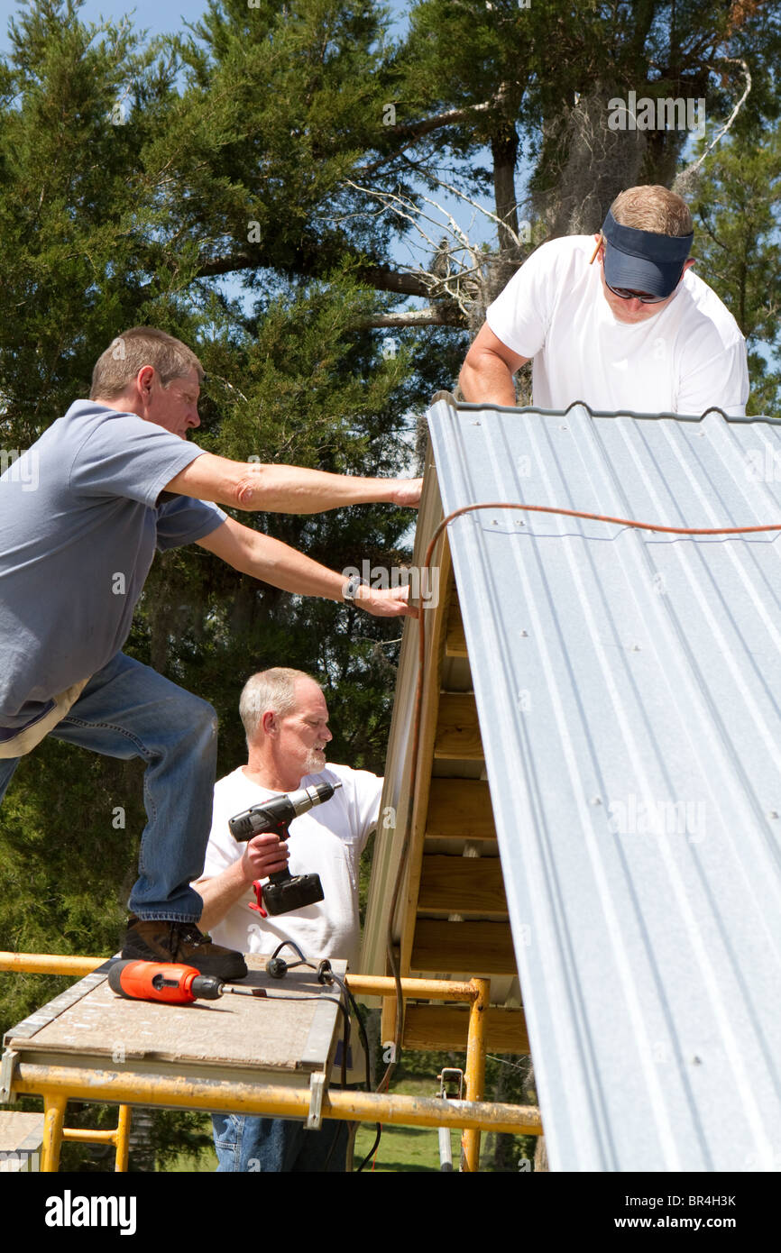 Construction work crew stands on scaffolding to attach sheet metal to