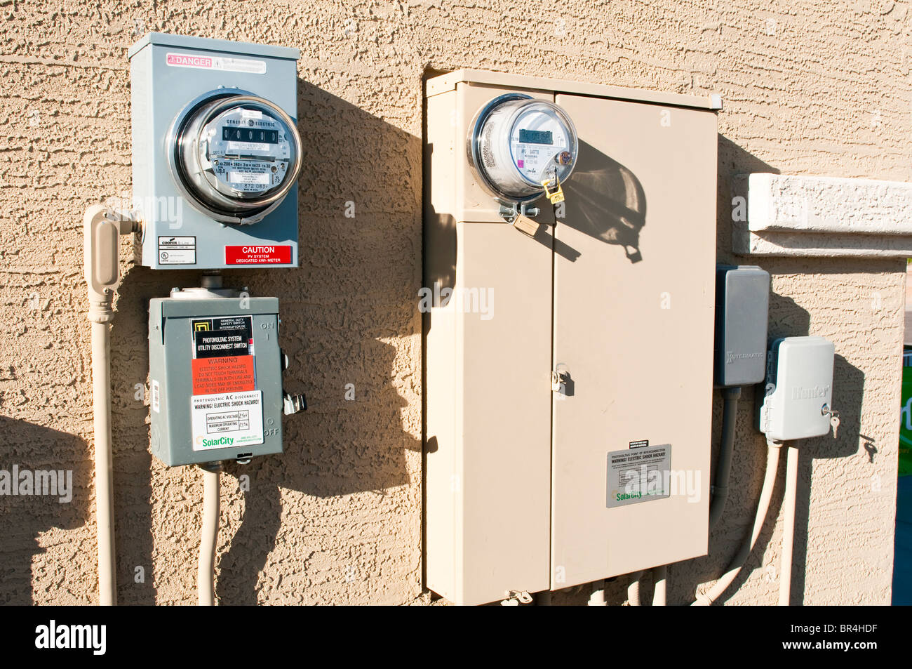 Interconnection circuitry enclosed in electrical panels connect solar energy to conventional sources on the side of a house. Stock Photo