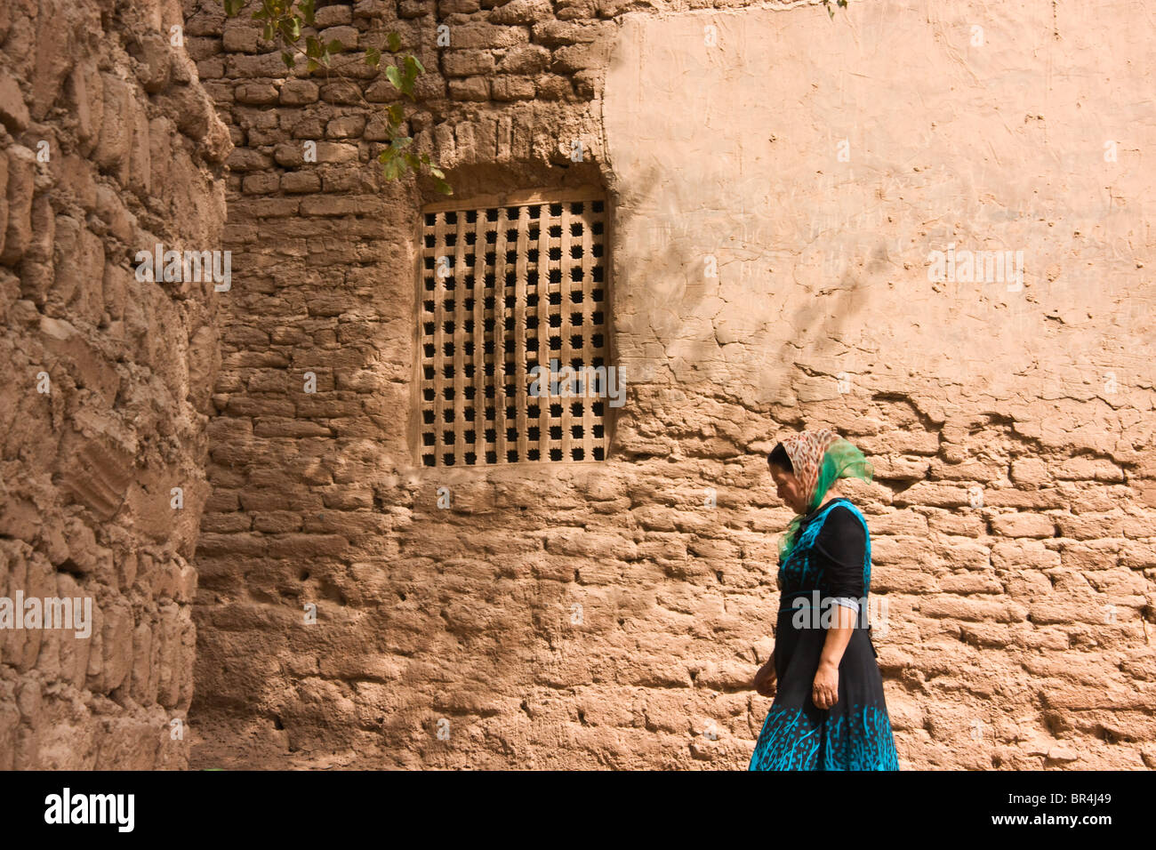 Uighur woman with traditional style clay houses,Turpan, Xinjiang, China Stock Photo