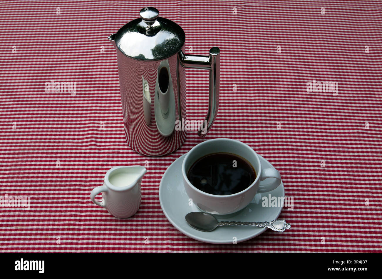 https://c8.alamy.com/comp/BR4JB7/a-shiny-coffee-pot-and-cups-and-saucers-on-a-red-and-white-tablecloth-BR4JB7.jpg