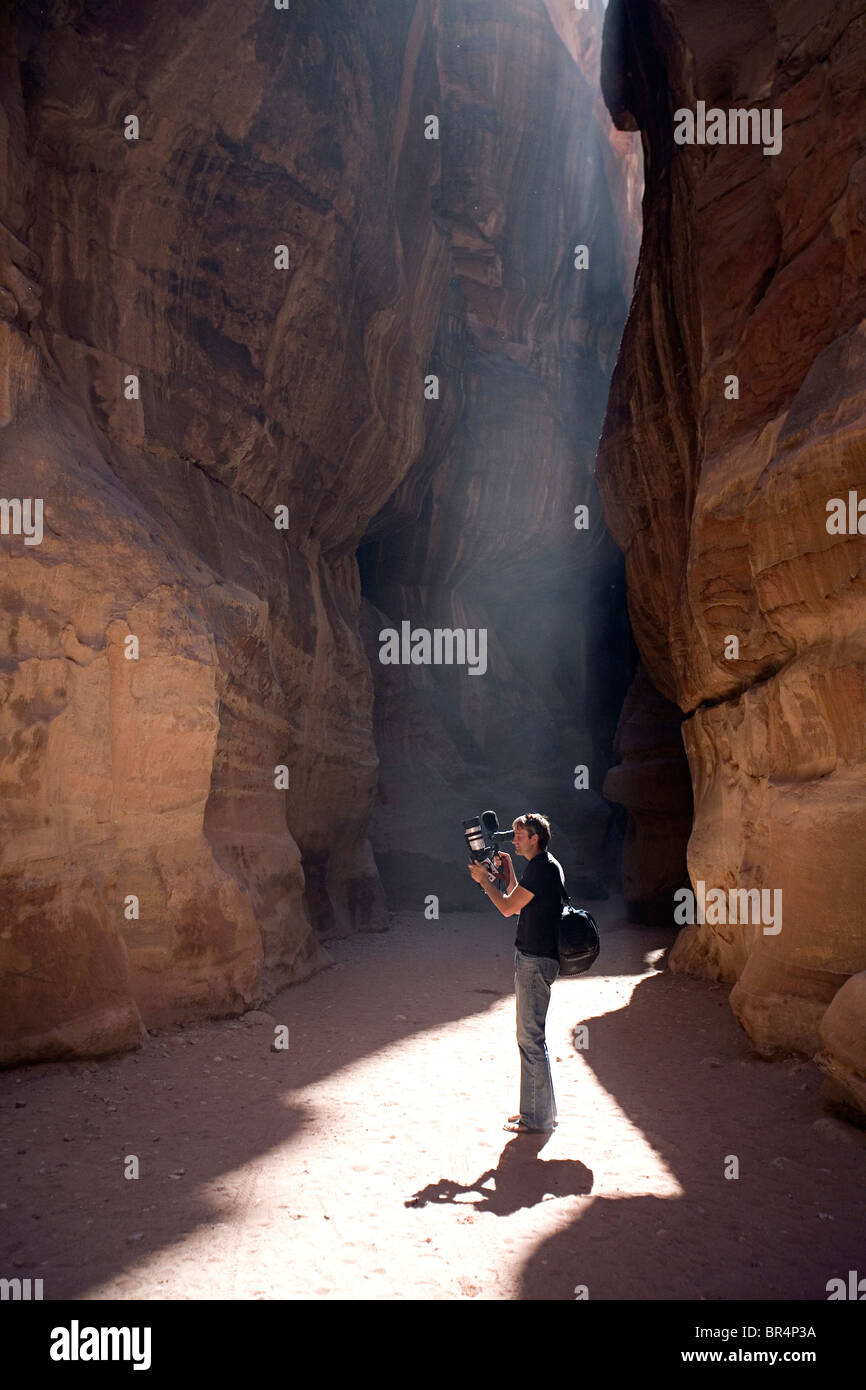 Man holding a Canon XL1 camera filming in a narrow ravine. Stock Photo