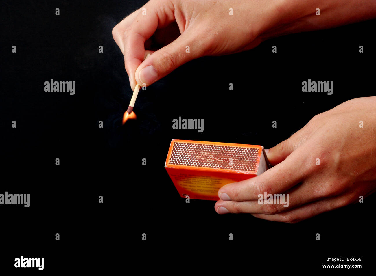 Hand striking a match while the other hand is holding the matchbox