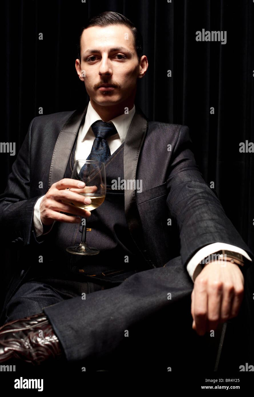 Portrait of a gentleman sitting and holding a glass of wine at a bar, London, England, UK Stock Photo