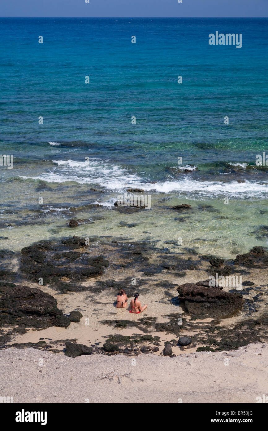 Girls sitting in sea at Calleta de Congrio beach, Papagayo, Playa