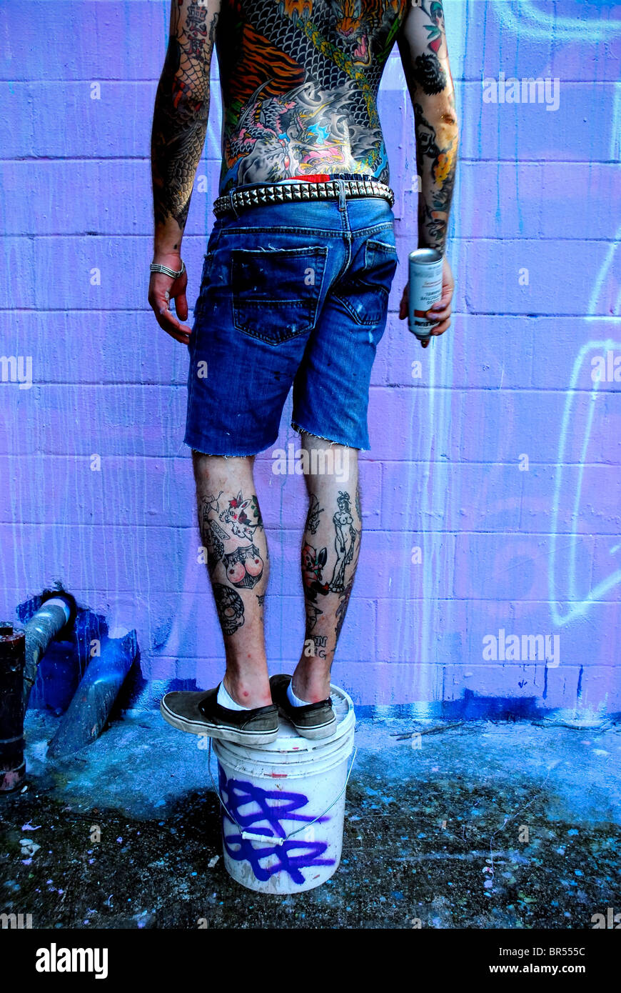 Graffiti artist with tattoos paints in Austin Texas. Stock Photo