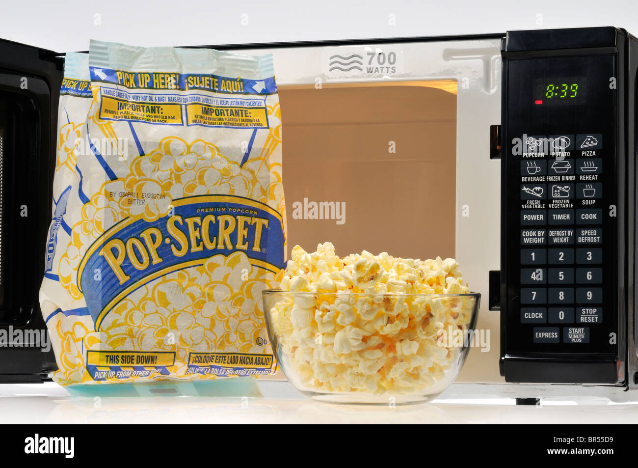 Open bag of Pop Secret with a glass bowl of cooked popcorn and