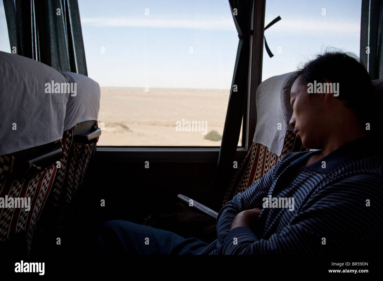 Man sleeping on a bus crossing the desert in China near Dunhuang. Stock Photo